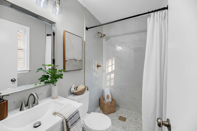 bathroom with vanity, toilet, and tiled shower