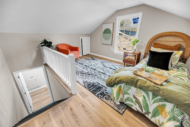 bedroom featuring baseboards, wood finished floors, and vaulted ceiling