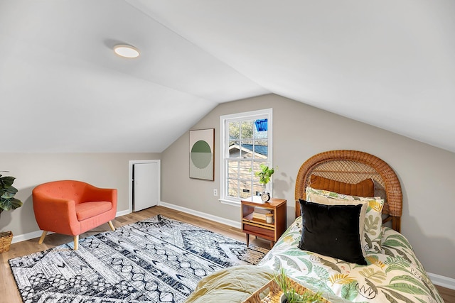 bedroom featuring baseboards, lofted ceiling, and wood finished floors