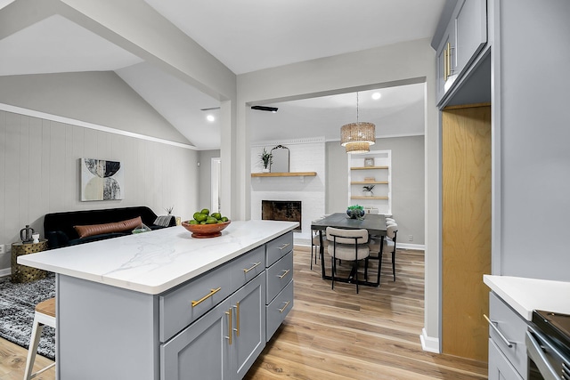 kitchen with a brick fireplace, gray cabinets, light wood-style floors, and open floor plan