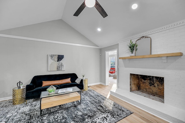 living room with lofted ceiling, light wood-style flooring, a fireplace, and ceiling fan