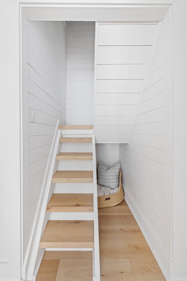 stairs with hardwood / wood-style floors and wooden walls