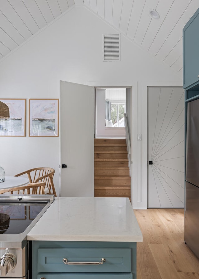 kitchen with fridge, stainless steel stove, light wood-type flooring, and wood ceiling