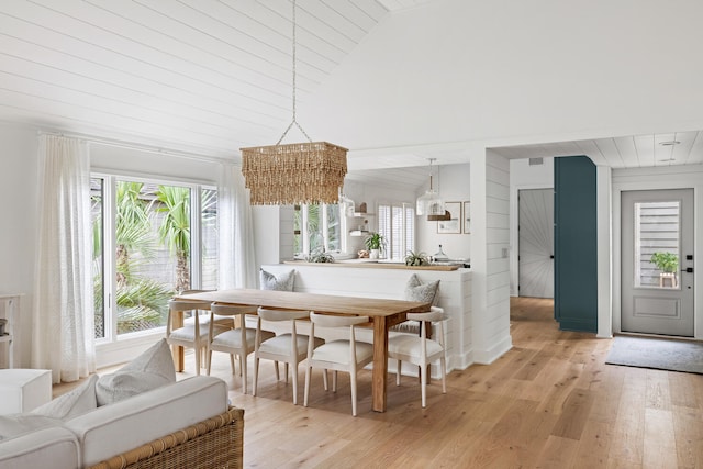 dining space featuring high vaulted ceiling and light hardwood / wood-style flooring