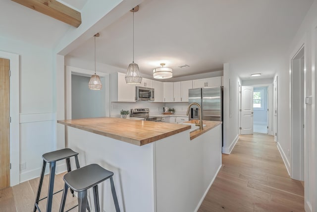 32 Briarcliff Dr, Charleston, SC 29407 - kitchen with appliances with stainless steel finishes, wooden counters, a breakfast bar, light wood-style floors, and tasteful backsplash