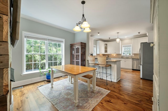 dining room with an inviting chandelier, ornamental molding, light hardwood / wood-style floors, and sink