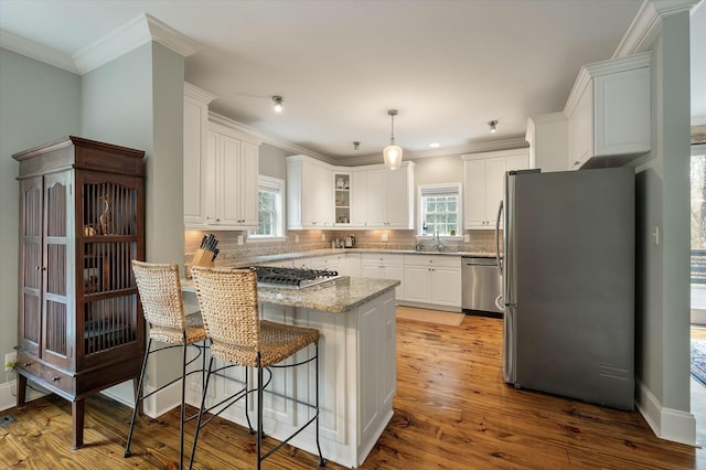 kitchen with light hardwood / wood-style floors, sink, hanging light fixtures, appliances with stainless steel finishes, and white cabinets