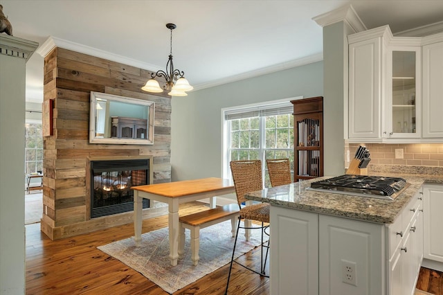 dining area featuring crown molding, a multi sided fireplace, light hardwood / wood-style flooring, and a notable chandelier