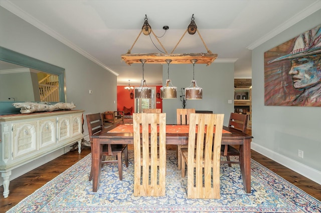 dining space with dark wood-type flooring, ornamental molding, and an inviting chandelier