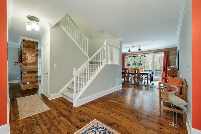 stairs with ornamental molding, a chandelier, and hardwood / wood-style floors