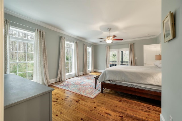 bedroom featuring ceiling fan, access to exterior, wood-type flooring, and multiple windows