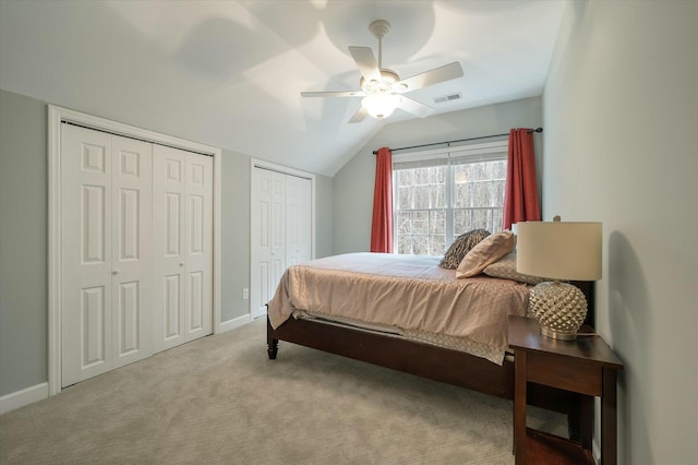 bedroom featuring ceiling fan, multiple closets, light carpet, and lofted ceiling