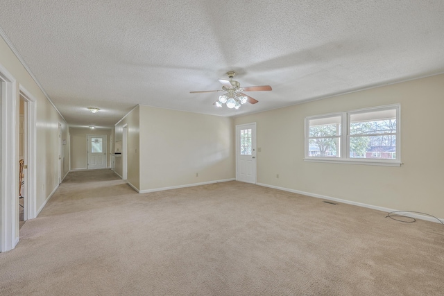 spare room featuring light carpet, a textured ceiling, a ceiling fan, and baseboards