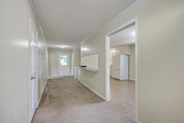 corridor featuring a textured ceiling, ornamental molding, baseboards, and light carpet