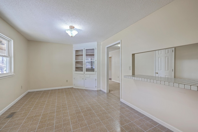 empty room featuring visible vents, baseboards, and a textured ceiling