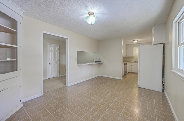 unfurnished living room with baseboards, a textured ceiling, and light floors