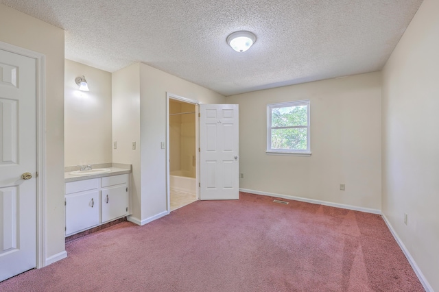 unfurnished bedroom featuring visible vents, a sink, connected bathroom, carpet floors, and baseboards