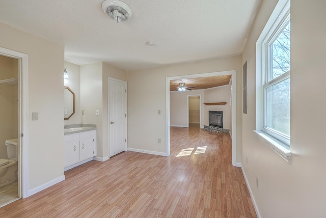 interior space featuring a brick fireplace, light wood-style floors, baseboards, and a sink