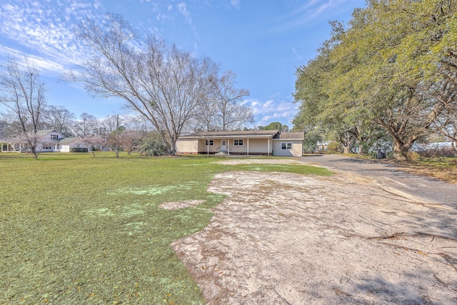 view of front of home featuring a front lawn and dirt driveway