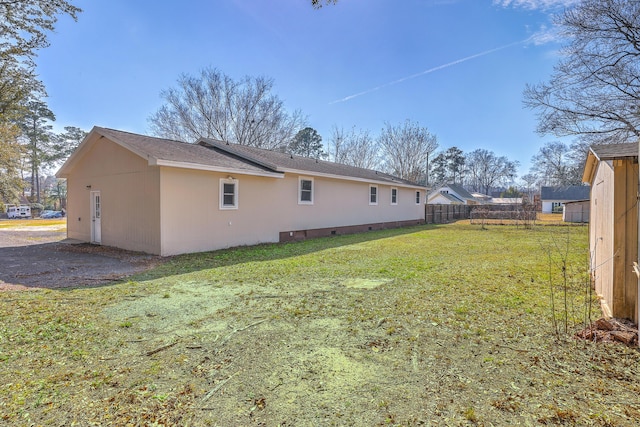 rear view of house with a yard, fence, and crawl space