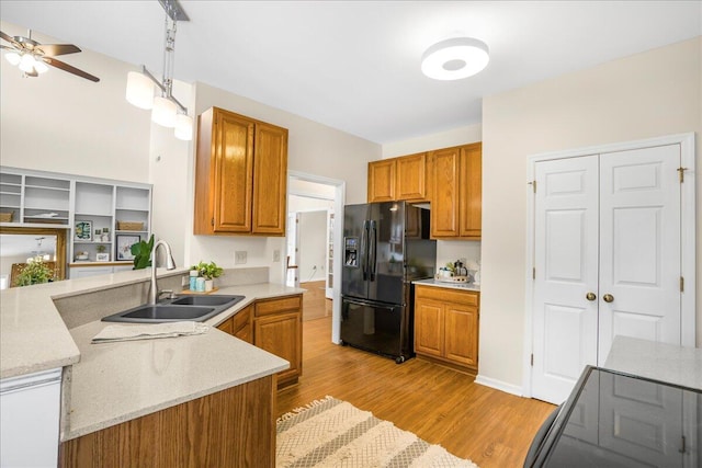 kitchen with black refrigerator with ice dispenser, sink, light hardwood / wood-style flooring, pendant lighting, and ceiling fan