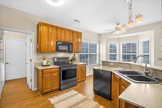 kitchen featuring pendant lighting, black appliances, light hardwood / wood-style floors, sink, and ceiling fan