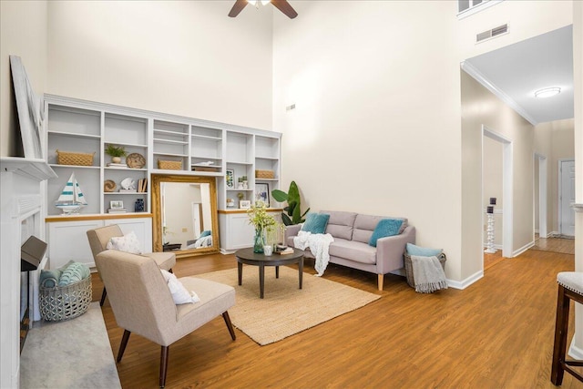 living room featuring built in features, hardwood / wood-style flooring, a high ceiling, and ceiling fan