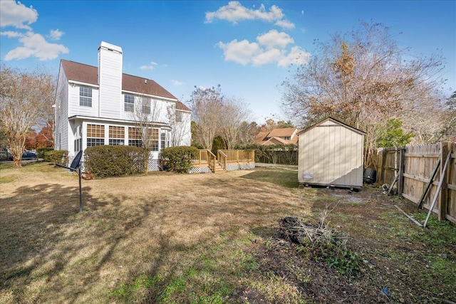 back of house featuring a wooden deck, a yard, a sunroom, and a storage unit