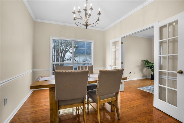 dining area with a notable chandelier, french doors, hardwood / wood-style floors, and ornamental molding