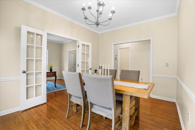 dining area featuring hardwood / wood-style flooring, crown molding, french doors, and an inviting chandelier