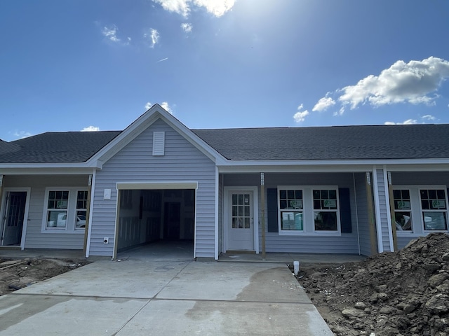 ranch-style house with a shingled roof, a porch, an attached garage, and driveway