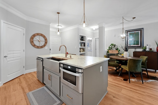 kitchen featuring pendant lighting, gray cabinets, a kitchen island with sink, and light hardwood / wood-style flooring