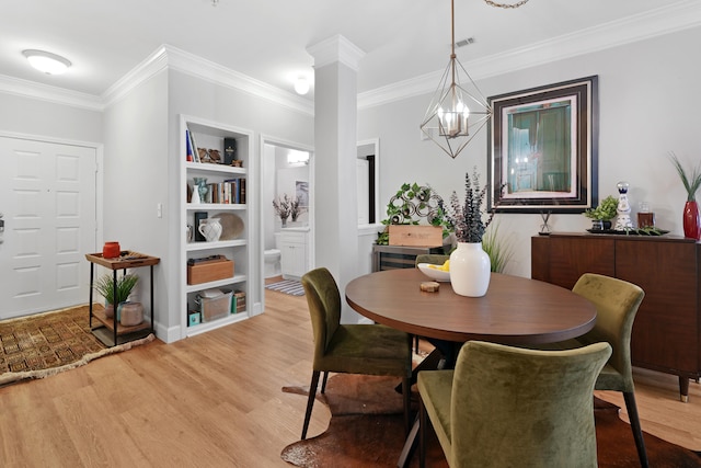 dining area with ornate columns, a notable chandelier, ornamental molding, and light hardwood / wood-style floors