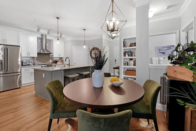 dining area with light hardwood / wood-style floors, crown molding, and a chandelier