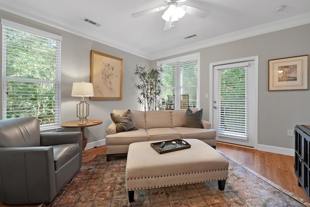 living room featuring ceiling fan, a healthy amount of sunlight, crown molding, and dark hardwood / wood-style flooring