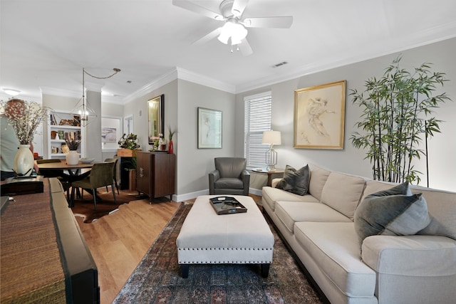 living room featuring ceiling fan with notable chandelier, crown molding, and hardwood / wood-style floors