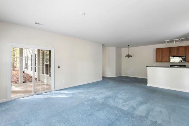 unfurnished living room featuring carpet flooring and rail lighting