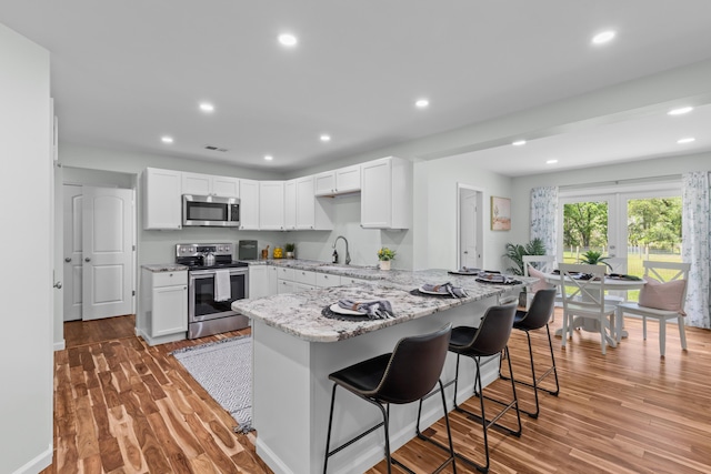 7239 Commodore Rd, Hollywood, SC 29449 - kitchen featuring stainless steel appliances, a kitchen bar, light stone countertops, light wood-style floors, and recessed lighting