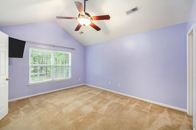 spare room featuring visible vents, ceiling fan, vaulted ceiling, and light carpet