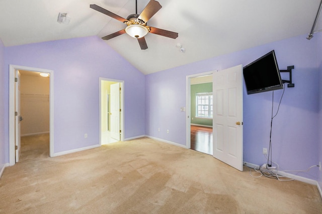 unfurnished bedroom with a walk in closet, baseboards, vaulted ceiling, and carpet floors