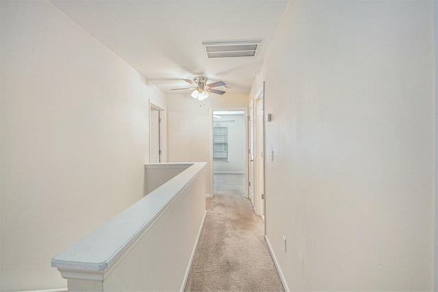 hall featuring light carpet, an upstairs landing, visible vents, and baseboards