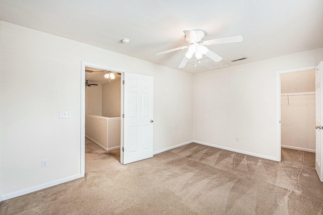 unfurnished bedroom with visible vents, baseboards, a closet, carpet floors, and a walk in closet