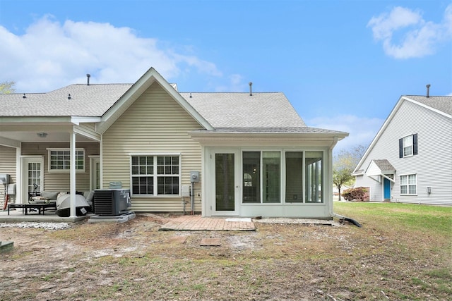 back of house with a shingled roof, a sunroom, a patio area, a yard, and cooling unit