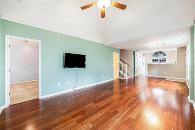 unfurnished living room with wood-type flooring, ceiling fan, baseboards, and stairs