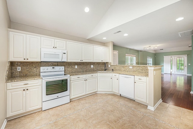 kitchen with tasteful backsplash, white appliances, a peninsula, visible vents, and lofted ceiling