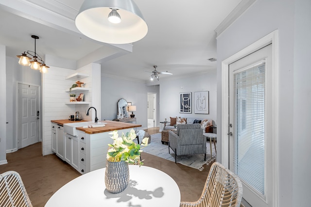 dining space with ceiling fan, light wood-type flooring, ornamental molding, and sink