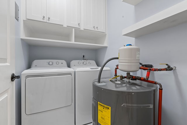 laundry area with cabinets, electric water heater, and separate washer and dryer