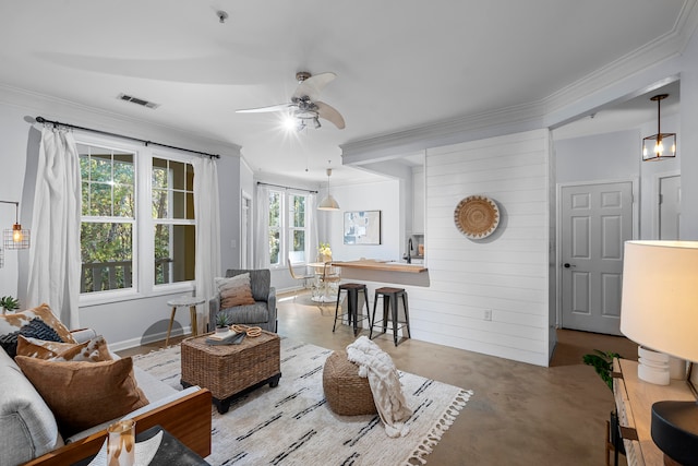 living room featuring ornamental molding, wooden walls, ceiling fan, and a healthy amount of sunlight