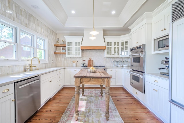 3130 Pignatelli Cres, Mount Pleasant, SC 29466 - kitchen with stainless steel appliances, wood-type flooring, a tray ceiling, glass insert cabinets, and ornamental molding