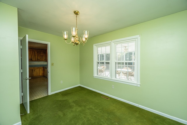 spare room featuring an inviting chandelier and dark carpet